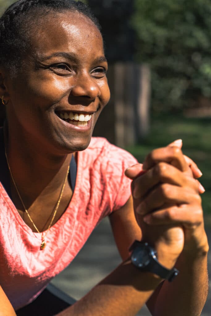 un coach de sport à Toulouse Coach sportive souriante en plein exercice de gainage en extérieur à Toulouse – motivation, bien-être et sport au grand air.
